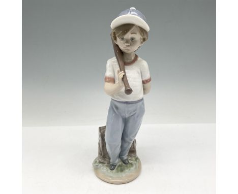 Glossy porcelain figure of a boy looking downwards holding his baseball bat in his right hand and a ball in his left. Lladro 