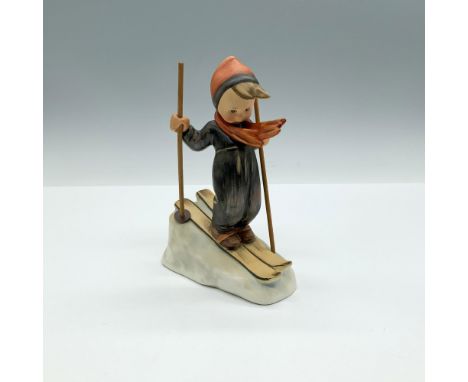 A matte hand painted figure of a boy dressed in winter attire, skiing down an icy slope, holding wooden poles. Goebel backsta