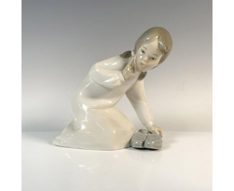 Glossy finish figurine of little girl crouching down to pick up slippers. Lladro backstamp. Artist: Vincente MartinezIssued: 