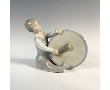 Glossy figure of a young boy banging a large drum. Lladro backstamp. Artist: Juan HuertaIssued: 1969-1979Dimensions: 6"L x 3.