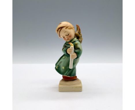 A matte hand painted figure of an angelic child wearing a robe decorated with stars while holding a lit candle. Goebel backst