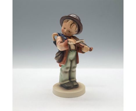 A hand painted figure of a boy carrying an umbrella and bag while playing the violin. Goebel backstamp. M.I. Hummel impressed