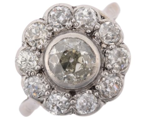 An early 20th century 18ct white gold diamond flowerhead cluster ring, rub-over set with old European and old-cut diamonds, p