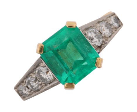 An 18ct gold Colombian emerald and diamond ring, centrally claw set 2.4ct emerald step-cut emerald, flanked by graduated mode