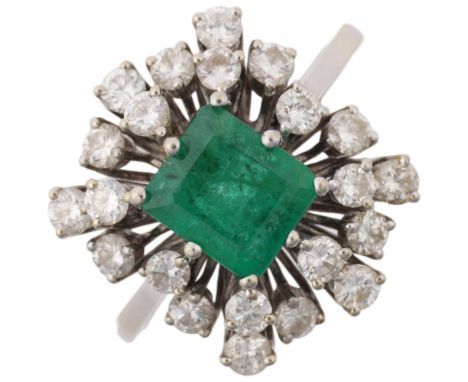 A late 20th century 18ct white gold emerald and diamond cluster cocktail ring, centrally claw set with 1ct emerald-cut emeral