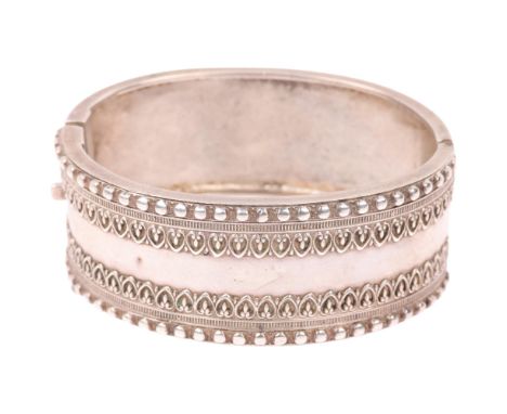 A Victorian sterling silver hinged bangle, with relief heart decoration, band width 24.8mm, internal circumference 16cm, 29.9