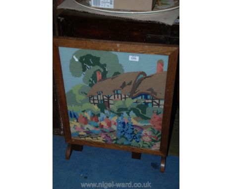A wooden Table/Firescreen with embroidery of a thatched cottage garden scene.