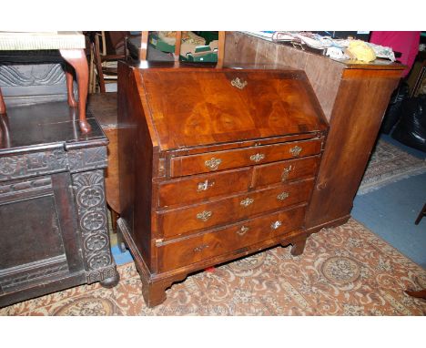 A Georgian Walnut Bureau having strip veneered top over the cross-banded strip veneered fall front, opening to reveal eight p