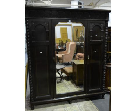 Carved oak triple wardrobe, demi lunette frieze, central mirror panel door flanked by arcaded panels, bobbin moulded outlines