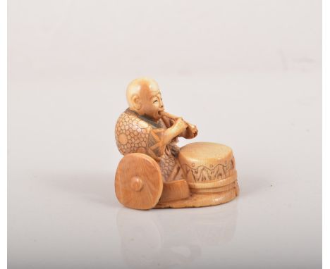 Japanese stained ivory Netsuke, modelled as a seated figure with a drum and cymbal, 4.5cm.