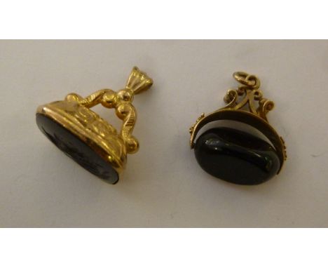 A 9ct gold pendant seal, set with a rotating onyx bead; and another cast with scrolls, the onyx tablet featuring an engraved 
