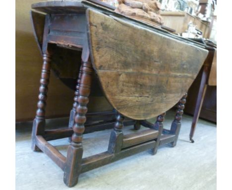 An early/mid 18thC and later country made oak gateleg table, the planked, oval top over an end drawer, raised on bobbin turne