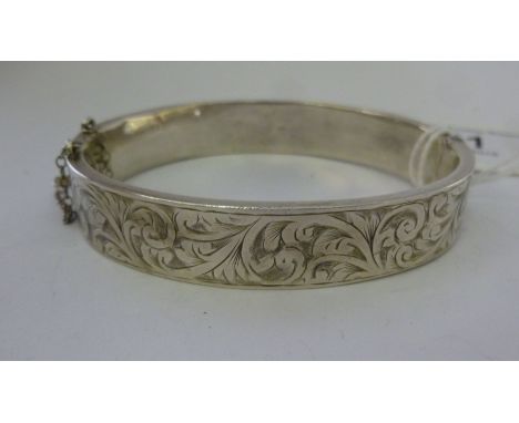 A hollow, hinged silver bangle with bright cut engraved foliate scrolled decoration       11