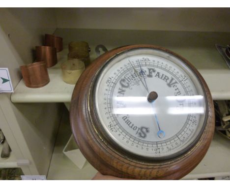 An early 20thC aneroid barometer, on a turned oak backplate  10''dia; a set of three scrolled copper napkin rings; and three 