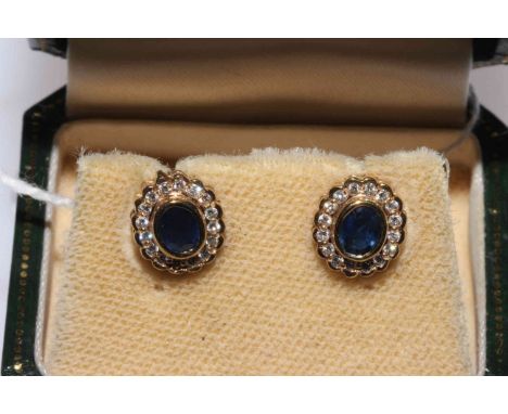 Pair sapphire and diamond oval earrings, each centre sapphire bordered with sixteen diamonds set in 9 carat gold, boxed.