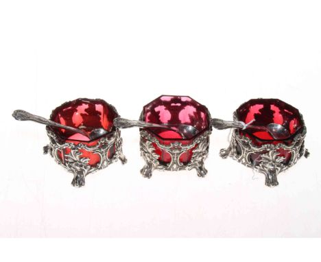 Set of three Victorian ornate silver plated open salts with ruby glass liners, with Kings pattern spoons.
