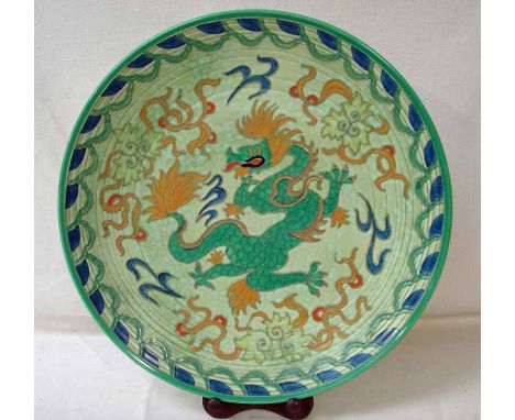 A Crown Ducal Charlotte Rhead dish decorated with a dragon on a green ground, signed by artist and bearing fading stamp to ba