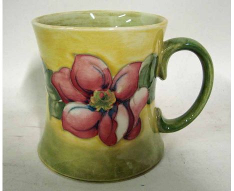 A William Moorcroft pottery mug of waisted cylindrical form, applied loop handle, tubeline decorated with a band of flowering