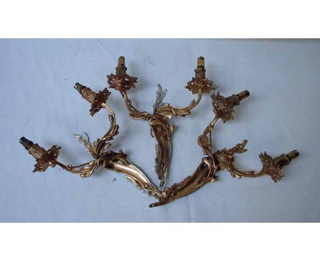 A set of three late 19th/20th century Rococco style ormolu twin light wall sconces of foliate form with electric light fittin