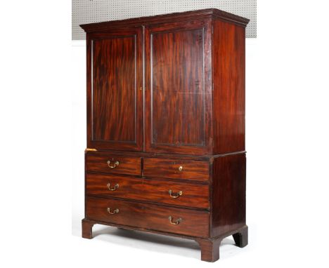 A George III mahogany compactum linen press, the recessed cupboard doors revealing three sliding drawers and a hanging space,