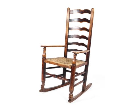 A 19th century oak ladder back rocking chair, with rush seat, on turned legs and baluster stretchers, 108 cm high