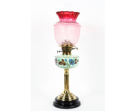 An Edwardian brass-mounted oil lamp with cranberry glass shade, the shade etched with fan ornament above green opaque glass r