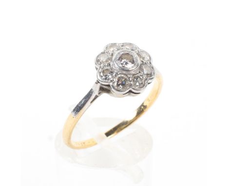 An 18ct gold and platinum diamond set flower ring. Central collete set old brilliant cut diamond with a surround of eight sin