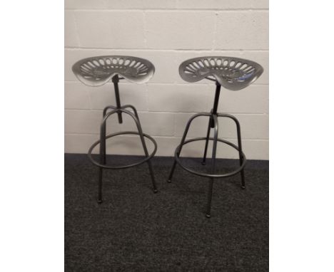 A pair of mid-century style industrial tractor seat counter stools with adjustable heights. 