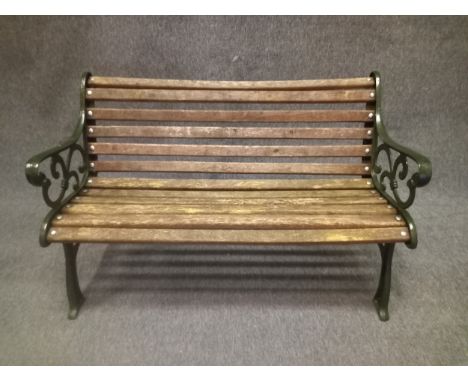 A contemporary painted cast iron garden bench in the 19th century style with scrolling openwork decoration and teak slats. W.