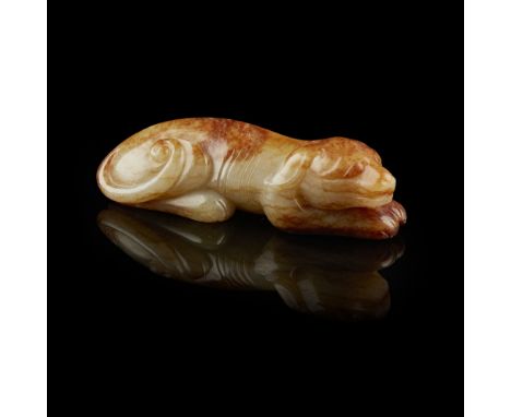 CELADON AND RUSSET JADE CARVING OF A HOUNDnaturalistically worked with the front paws outstretched and the rear legs tucked u