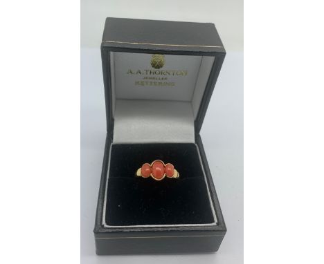 A 9ct gold lady's dress ring set with 3 coral stones, size M.Condition ReportGood condition.