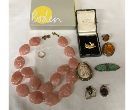 A small selection of costume jewellery including a yellow metal ring, a Caroline Charles rabbit brooch, an amber brooch and r