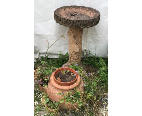 A reconstituted stone tree trunk bird bath and a terracotta planter. Bird bath 74cms h x 42cms w at top.Condition ReportWeath