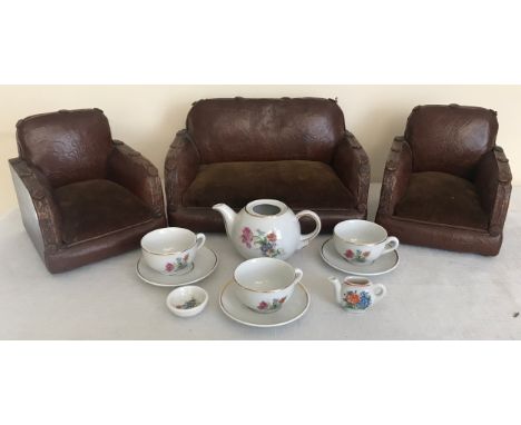 A Dolls House sofa and 2 armchairs in brown rexine. Sofa 26cms w x 15cms h. and a child's tea set.Condition ReportSuite with 