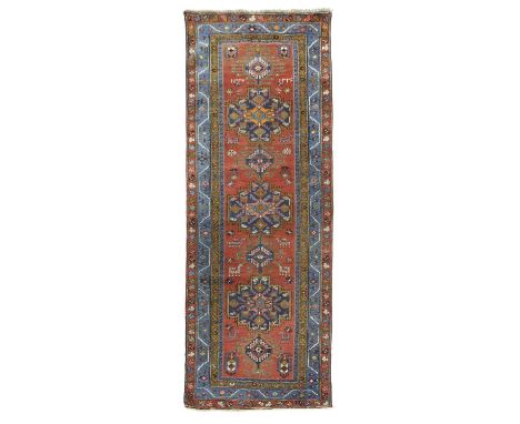 A HERIZ RUNNERAZERBAIJAN, INDISTINCTLY DATED, C.1910the madder field with a column of serrated stepped indigo medallions flan