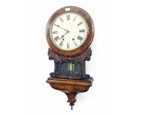 Walnut two train 12" drop dial wall clock, within a flat canted surround over a pendulum window flanked by carved foliage ove