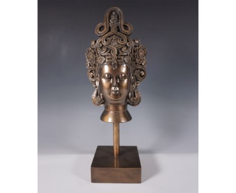 A striking Balinese-style bust sculpture cast in bronze, featuring an intricately detailed headdress with floral and scrollin