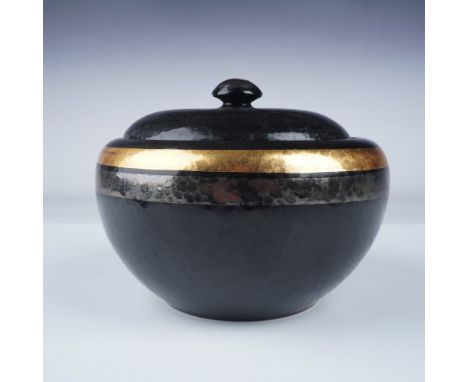 Refined black ceramic lidded jar featuring a textured surface and striking gold bands encircling the body. The piece showcase