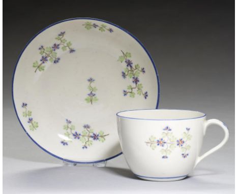 A PINXTON TEACUP AND SAUCER, 1796-1813  pattern 14, enamelled in blue and green with pink accents with sprigs, blue enamel ri