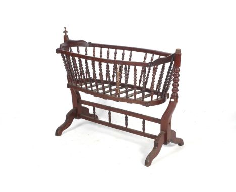 A Victorian mahogany cradle child's crib. The swinging bobbin turned cradle raised on barley twist supports and shaped feet, 