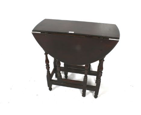 An 18th century small oak gate leg table. Of oval form, with a single frieze drawer with front to back lining, vase turned le