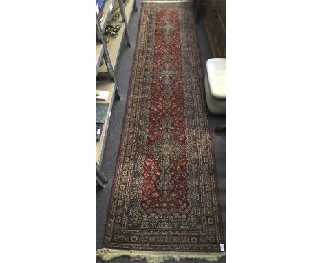 A Persian style woollen carpet runner. With a red background, multi borders and floral decoration runner. 340cm x 80cm