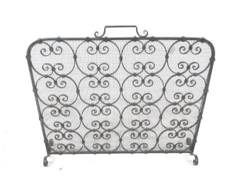 A 20th century wrought metal work fire screen. Geometric scroll work decoration, wire mesh to the back with carry handle and 