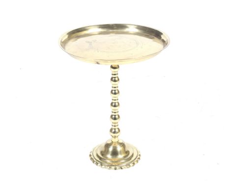 A 20th century brass occasional table. With a circular top, mounted on a bobbin support with a tapered circular base with flu