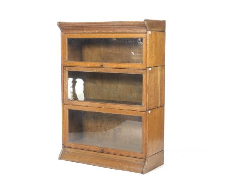 A Globe Wernicke style oak freestanding three sectional library bookcase. With up and over glazed doors, raised on a moulded 