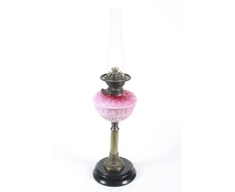 A Wright & Butler of Birmingham oil lamp. Having a black ceramic base, brass columnar stand and a graduated pink glass reserv