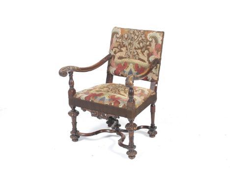 A William and Mary walnut open armchair. With carved acanthus and outswept arms and a needlepoint seat and back covering depi
