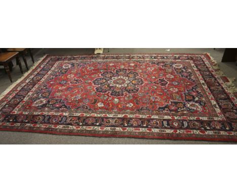 A large Persian Bakhtiari style wool carpet rug. On a red and dark blue ground, multiple borders of geometric floral designs 