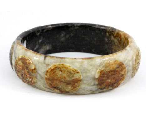 A Chinese mixed colour carved jade bangle, W. 2cm Internal Dia. 6.5cm.