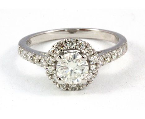 An 18ct white gold (stamped 750) diamond set halo ring with diamond set shoulders, with 0.70ct centre diamond, (O).